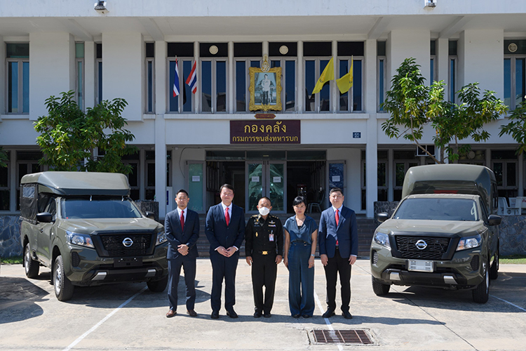 A group of people standing in front of two Navara's for the Army Transportation Dpeartment